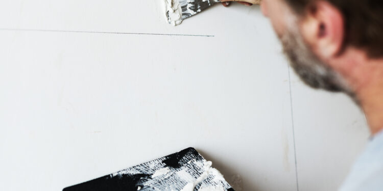 Bouwvakker schildert de muur na een scheur