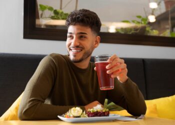 Halbnahe Aufnahme: Glücklicher Mann hält Tasse Holunderbeerensaft