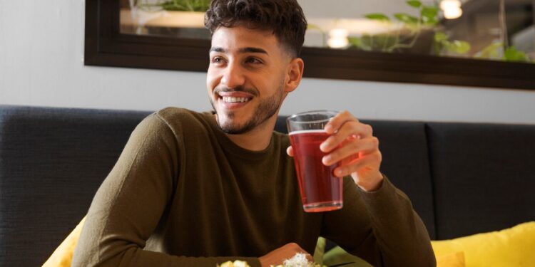 plan moyen d'un homme heureux tenant une tasse de jus de sureau
