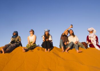 مجموعة-أشخاص-يجلسون-فوق-كثبان-الصحراء-المغربية