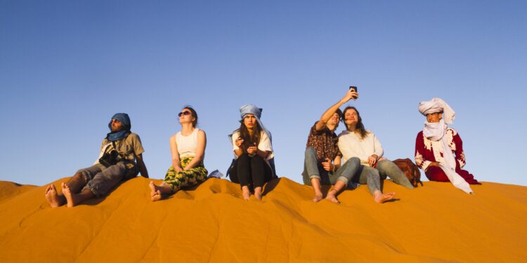 مجموعة-أشخاص-يجلسون-فوق-كثبان-الصحراء-المغربية