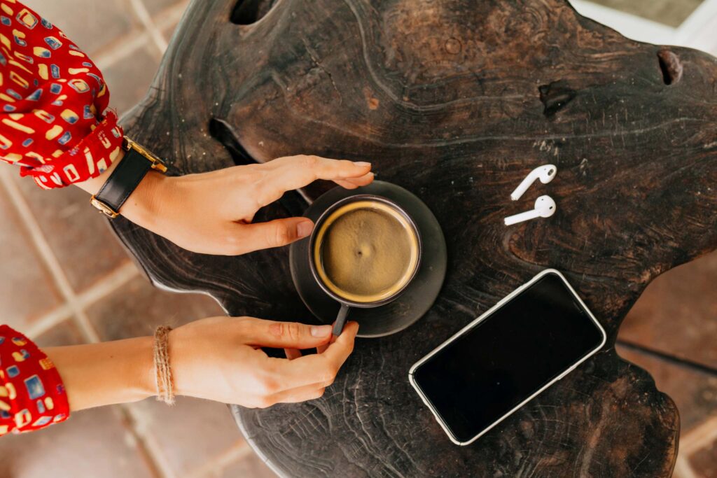 moroccan-woman-s-hand-holding-cup-coffee-with-headphones-smartphone