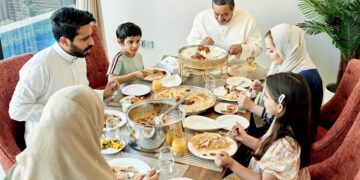 Moroccan family gathered around traditional Eid feast with couscous and tagine during holiday season celebrations, representing multicultural family traditions blending Islamic customs with Moroccan hospitality