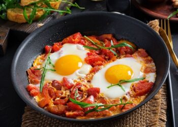 شقشقة مغربية تقليدية مع البيض المسلوق في صلصة طماطم محنكة مقدمة في الطاجين، تمثل خياراً إفطاراً صحياً خالياً طبيعياً من الجلوتين مثالي لمن يهتمون بصحتهم