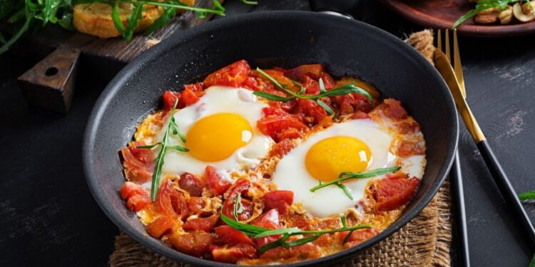 Shakshuka marroquí tradicional con huevos escalfados en salsa de tomate especiada servida en tajine, representando una opción de desayuno saludable y naturalmente sin gluten, perfecta para comensales preocupados por la salud