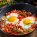 Traditional Moroccan shakshuka with poached eggs in spiced tomato sauce served in tagine, representing healthy naturally gluten-free breakfast option perfect for health-conscious diners