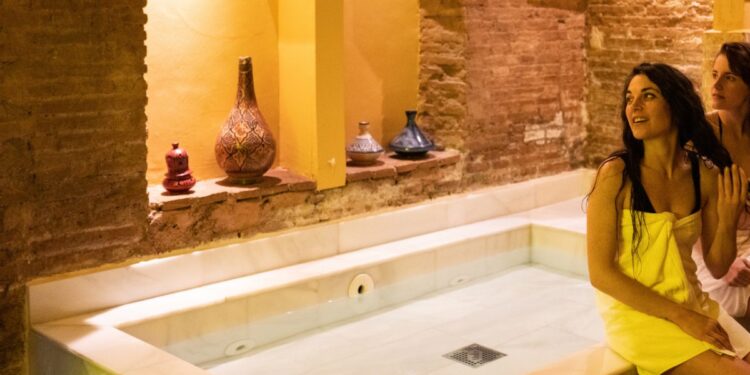 Een vrouw ontspant zich tijdens een traditioneel hammam ritueel in een met stoom gevulde Marokkaanse badhuizen, omgeven door warme tegelmuren.