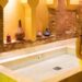 Hammam - MAwebzine Een vrouw ontspant zich tijdens een traditioneel hammam ritueel in een met stoom gevulde Marokkaanse badhuizen, omgeven door warme tegelmuren.
