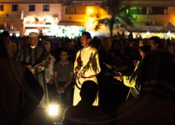 Een maalem-muzikant optredend tijdens het festivalseizoen van Marokko in Essaouira, met een menigte rond het open-air podium