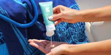 zonnebrand-aanbrengen-unsplash - MAwebzine Een Marokkaanse vrouw die zonnebeschermingscrème op haar gezicht aanbrengt op een zonnige straatje in de medina