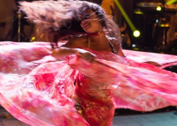 Een uitvoerder in traditioneel kostuum op het podium op het populair kunstfestival in Marrakech, omringd door een menigte 's nachts
