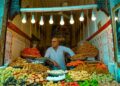 Een vrouw die Marokkaans straatvoedsel kiest bij een druk kraampje in de medina, een scène die de dagelijkse vreugde van veilig eten in Marokko vastlegt