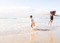 Een moeder en haar kinderen die kinderen koel houden op een zonnig Marokkaans Atlantisch strand, sprietend in ondiep water dicht bij de kust.