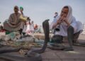 Een moeder en kind kijken samen naar straatartiesten, genietend van Marrakech-activiteiten op het beroemde Jemaa el-Fna plein