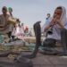 Een moeder en kind kijken samen naar straatartiesten, genietend van Marrakech-activiteiten op het beroemde Jemaa el-Fna plein