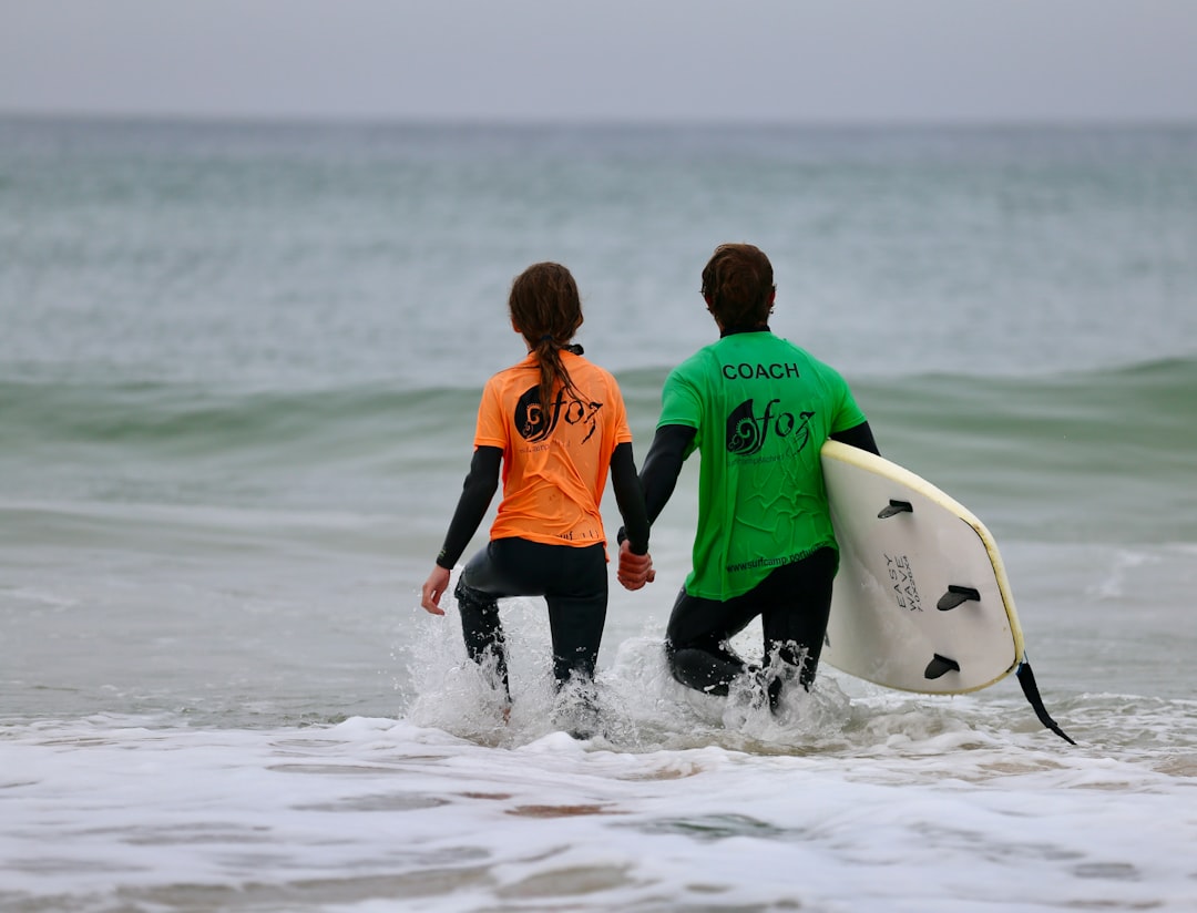 Een surfinstructeur begeleidt een beginnerstudent in een golf, een typische scène van surfen in Marokko kampen in de zomer