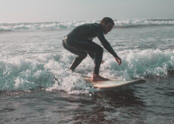 Een surfer rijdt een lange zachte golf langs de Marokkaanse Atlantische kust, wat de geest van surfen in Marokko in de zomer vastlegt