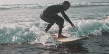 Een surfer rijdt een lange zachte golf langs de Marokkaanse Atlantische kust, wat de geest van surfen in Marokko in de zomer vastlegt