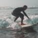 Een surfer rijdt een lange zachte golf langs de Marokkaanse Atlantische kust, wat de geest van surfen in Marokko in de zomer vastlegt