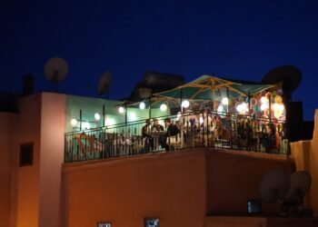 genieten van cocktails op een van de dakterrassen in Marrakech, met de moskee van Koutoubia op de achtergrond bij zonsondergang.