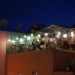 woman-drinking-cocktail-rooftop-marrakech-unsplash - MAwebzine genieten van cocktails op een van de dakterrassen in Marrakech, met de moskee van Koutoubia op de achtergrond bij zonsondergang.