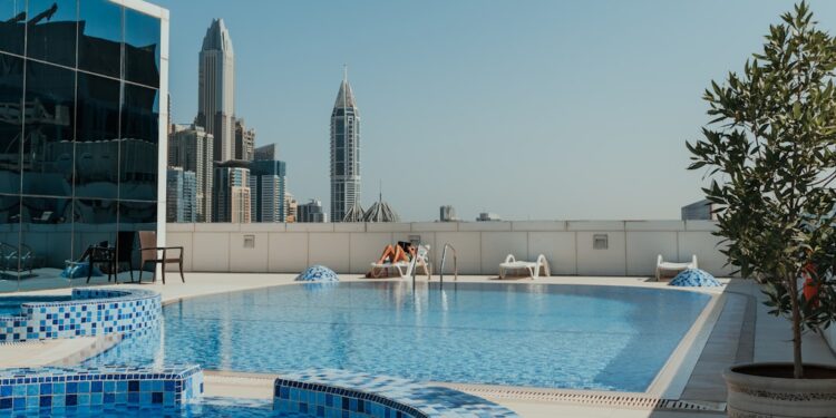 woman-swimpool-rooftop-unsplash - MAwebzine Eine Frau, die sich am privaten Pool auf dem Dach eines Riads entspannt, mit Blick auf die Skyline der Medina von Marrakesch bei Sonnenuntergang