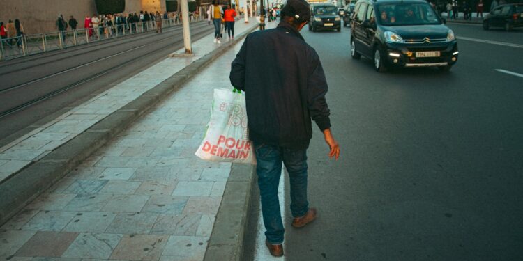 man-shopping-morocco-souk-tote-bag-unsplash - MAwebzine A traveller carrying a reusable tote bag to reduce plastic use while shopping in a Moroccan souk