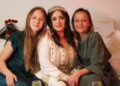 A Moroccan family dressed in traditional djellabas gathering outdoors during Fête du Trône festivities in a city medina