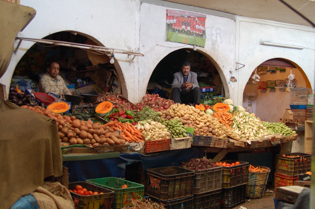A woman selecting ripe summer fruit at a Moroccan souk, reflecting how seasonal produce shapes summer cooking in Morocco