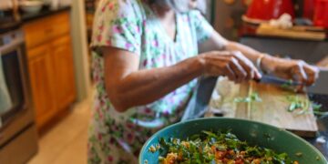 A Moroccan woman preparing a fresh zaalouk salad at home, showing how summer cooking in Morocco