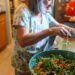 moroccan-woman-preparing-salad-unsplash - MAwebzine Een Marokkaanse vrouw die thuis een verse zaalouk-salade bereidt, met aandacht voor zomerkoken in Marokko