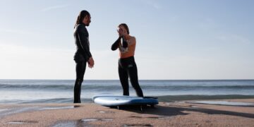 surf-instructor-teaching-beginner-on-beach-unsplash - MAwebzine A certified coach at one of Morocco's surf schools helps a beginner stand on a board for the first time on the Atlantic coast