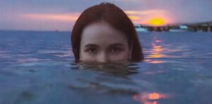 Une femme marche dans les eaux froides de l'Atlantique sur la côte marocaine, pratiquant la baignade en eau froide au lever du soleil près d'Essaouira.