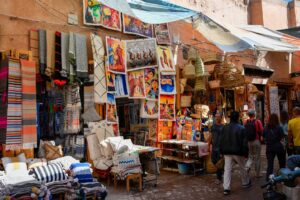 A muralist working on a large wall painting during the Asilah Moussem, with the whitewashed medina behind her
