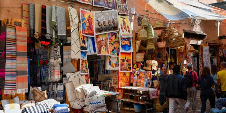 artist-painting-mural-morocco-medina-unsplash - MAwebzine A muralist working on a large wall painting during the Asilah Moussem, with the whitewashed medina behind her