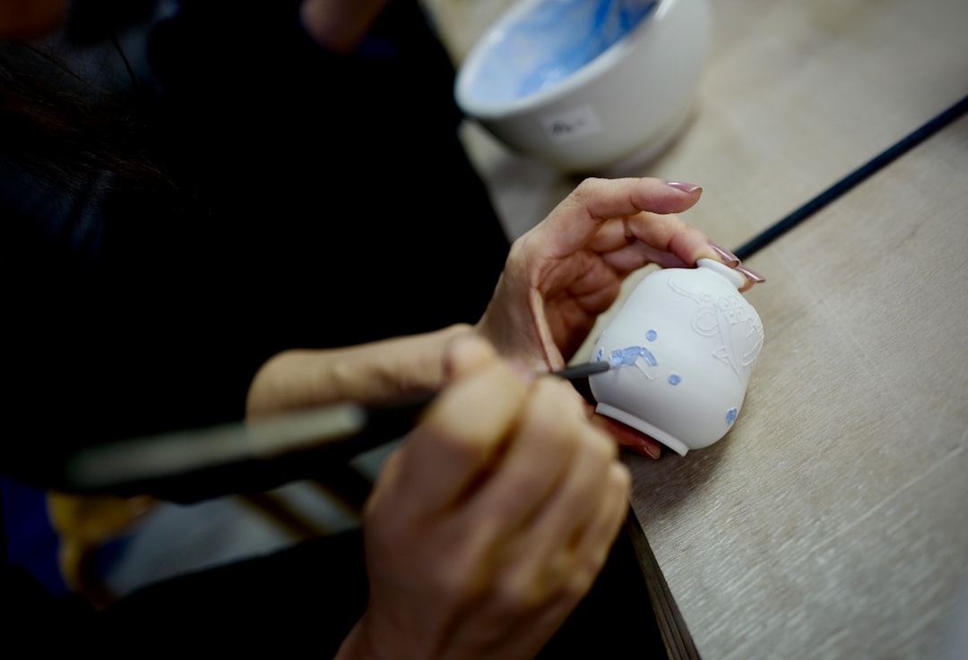 An artisan applies the iconic cobalt blue glaze to a piece of Moroccan pottery in a Fès workshop