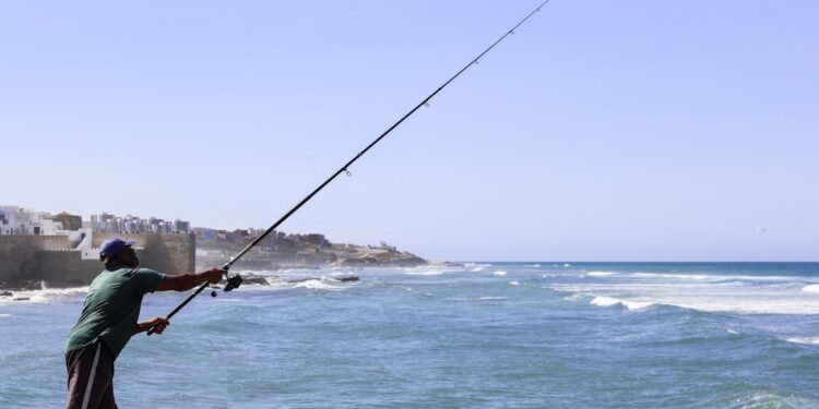 fisherman-morocco-port-morning-catch-unsplash - MAwebzine Een visser lost de verse vangst van de ochtend uit in een Marokkaanse kusthavenstad, de basis van alle kustmenu's in augustus.