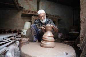 A Fassi artisan demonstrates Moroccan pottery hand-throwing technique on a foot-powered wheel in Ain Nokbi