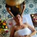 moroccan-spa-woman-unsplash - MAwebzine A Moroccan woman relaxing during an evening ritual in a traditional hammam setting, surrounded by soft candlelight.