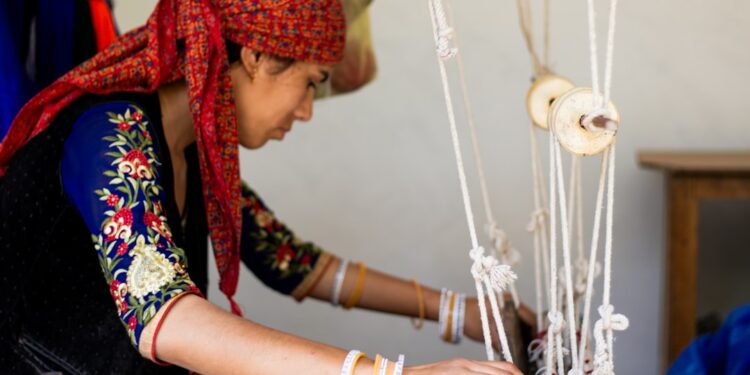 moroccan-woman-cooperative-weaving-unsplash - MAwebzine Eine Mitarbeiterin einer Frauenkooperative im ländlichen Marokko webt ein traditionelles Textil an einem gemeinsamen Werktisch