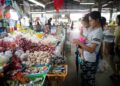 A mother and child selecting fresh vegetables together at a Moroccan souk, practicing Moroccan Arabic words for each item