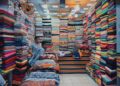 A person carefully inspects deadstock fabric rolls inside a Moroccan medina souk