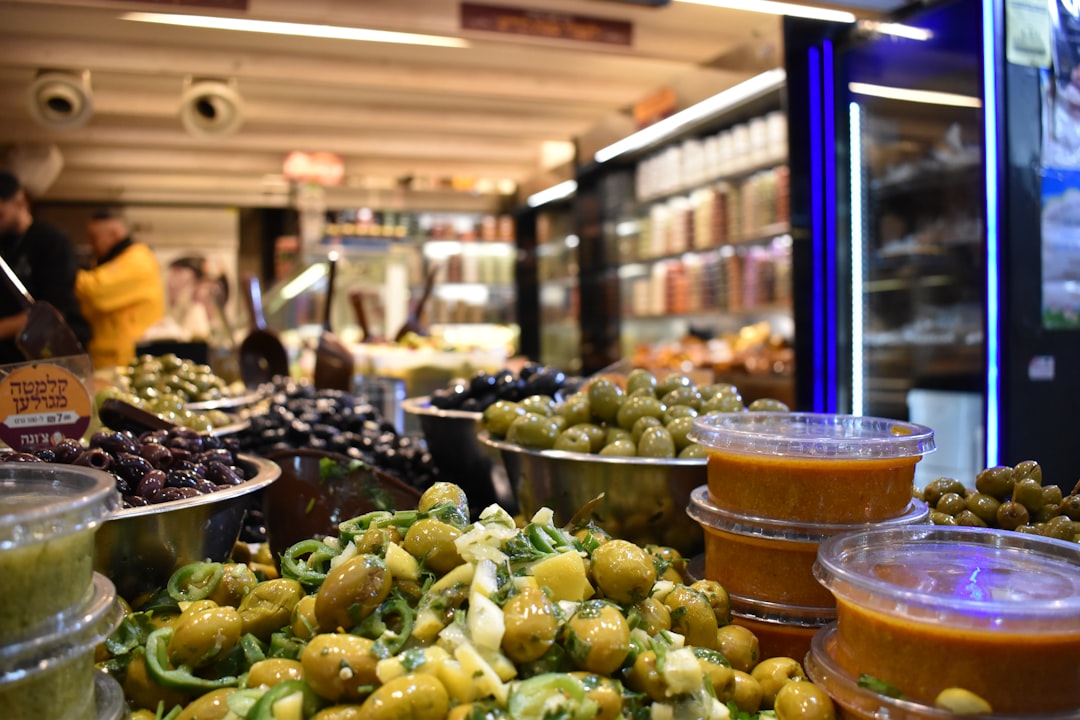 A shopper fills a glass jar with olives at Moroccan markets, choosing a plastic-free alternative at the souk counter.