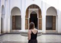 A woman sitting beside a central courtyard fountain in a traditional Moroccan riad, experiencing natural riad cooling.