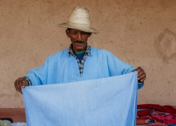 A Moroccan artisan weaving fabric inside a cooperative, showing the process behind building a capsule wardrobe