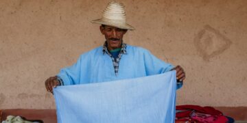 A Moroccan artisan weaving fabric inside a cooperative, showing the process behind building a capsule wardrobe
