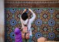 A Moroccan artisan woman arranging reclaimed zellige tiles to furnish a Moroccan home with medina materials