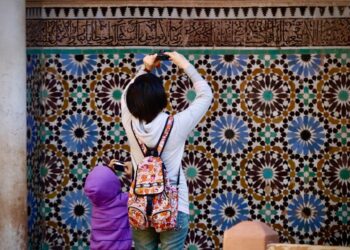 A Moroccan artisan woman arranging reclaimed zellige tiles to furnish a Moroccan home with medina materials