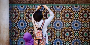 A Moroccan artisan woman arranging reclaimed zellige tiles to furnish a Moroccan home with medina materials