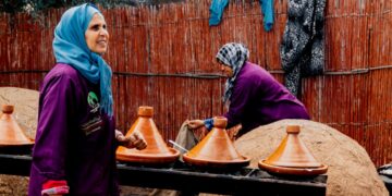 Una mujer marroquí preparando cuidadosamente un tagine tradicional, representando la profundidad de la cultura gastronómica marroquí transmitida.